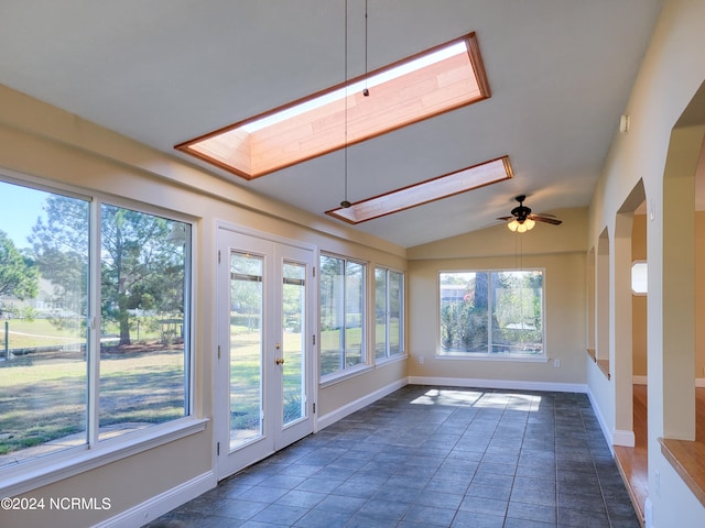 unfurnished sunroom featuring vaulted ceiling with skylight and ceiling fan