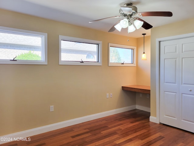 unfurnished bedroom featuring dark hardwood / wood-style flooring, built in desk, a closet, and ceiling fan