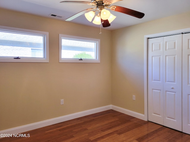 unfurnished bedroom featuring hardwood / wood-style floors, ceiling fan, a closet, and multiple windows