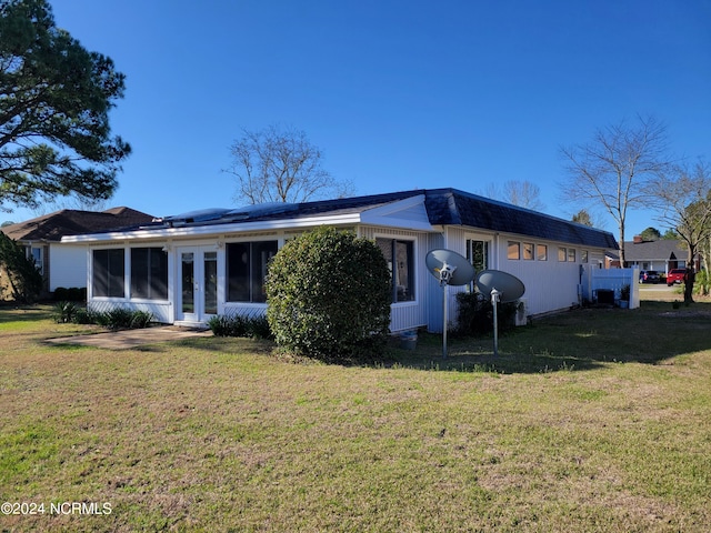 rear view of house with a sunroom and a yard