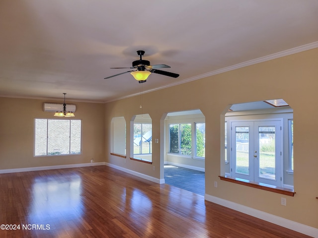 empty room featuring ceiling fan with notable chandelier, hardwood / wood-style flooring, a wall mounted AC, and ornamental molding