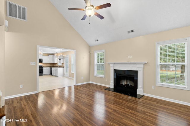 unfurnished living room with wood-type flooring, ceiling fan with notable chandelier, and high vaulted ceiling