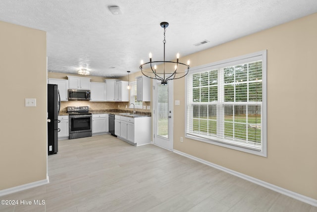 kitchen featuring sink, an inviting chandelier, pendant lighting, white cabinets, and black appliances