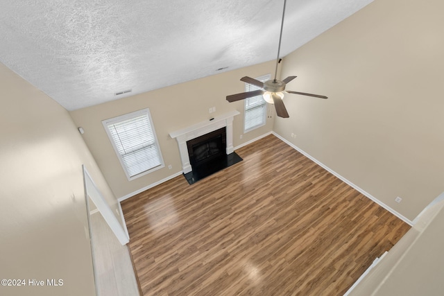 unfurnished living room featuring a textured ceiling, ceiling fan, lofted ceiling, and hardwood / wood-style flooring