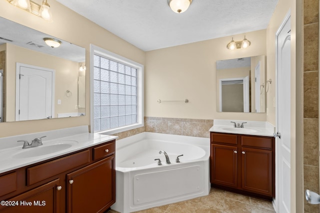 bathroom with a bathing tub, tile patterned flooring, vanity, and a textured ceiling