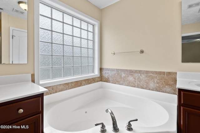 bathroom with a textured ceiling, vanity, and a bathtub