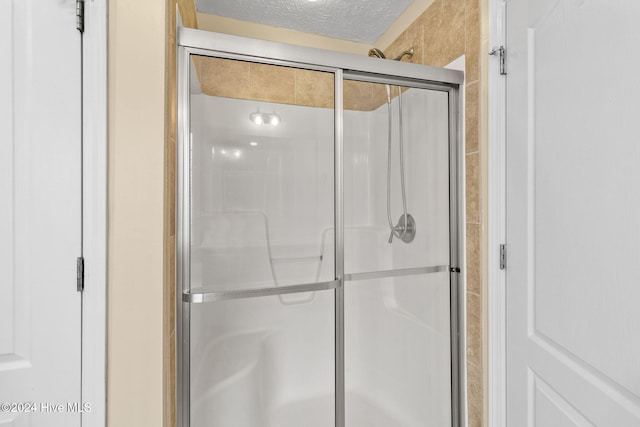 bathroom featuring an enclosed shower and a textured ceiling