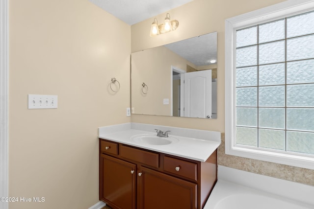 bathroom featuring a tub to relax in, vanity, and a textured ceiling