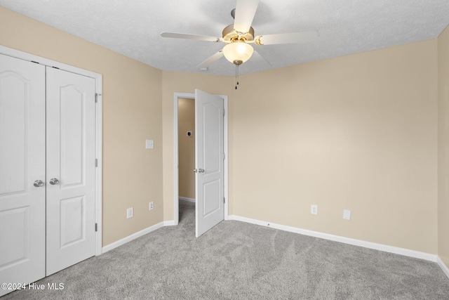 unfurnished bedroom featuring ceiling fan, light colored carpet, a textured ceiling, and a closet