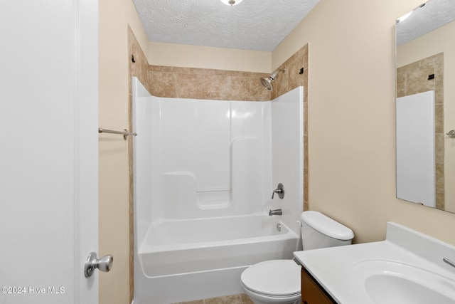 full bathroom with vanity, toilet, a textured ceiling, and tiled shower / bath combo