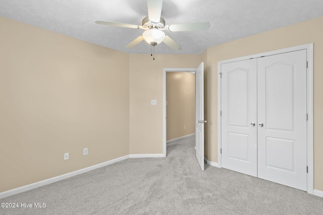 unfurnished bedroom with a textured ceiling, ceiling fan, light carpet, and a closet