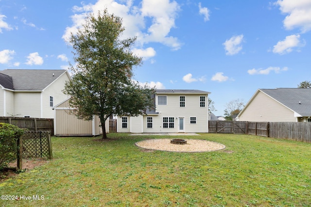 rear view of house with a shed, a yard, and an outdoor fire pit