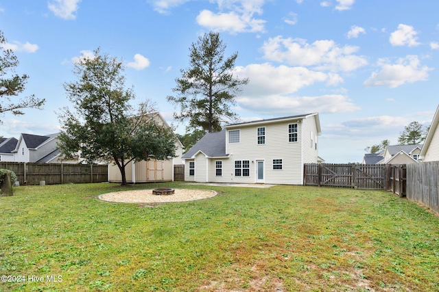 rear view of property featuring a lawn and an outdoor fire pit