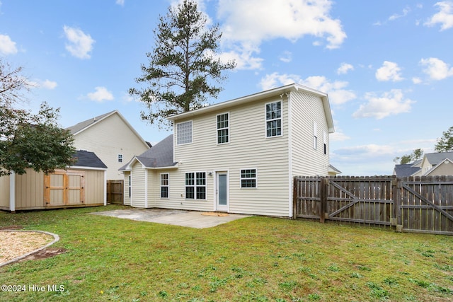 rear view of property featuring a storage unit, a patio area, and a lawn