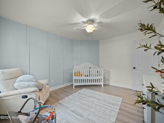 bedroom with ceiling fan, light hardwood / wood-style floors, and a nursery area