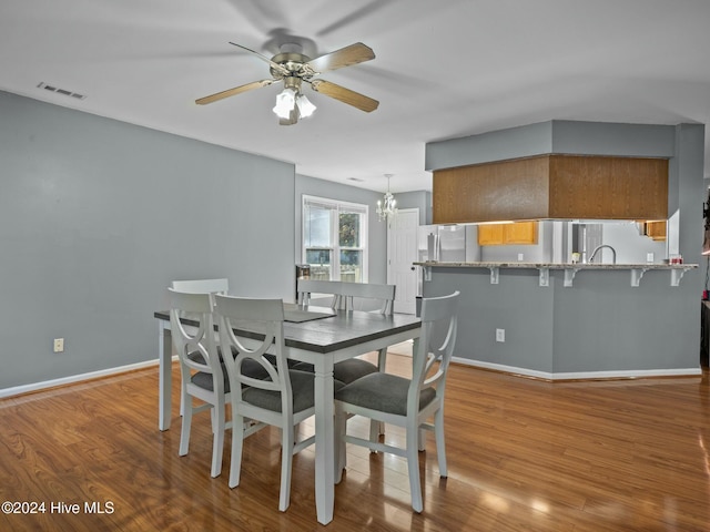 dining room with ceiling fan with notable chandelier and light wood-type flooring