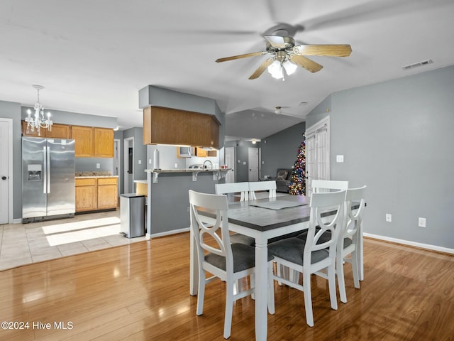 dining space with light hardwood / wood-style flooring, ceiling fan with notable chandelier, and sink