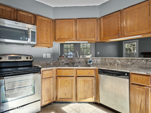 kitchen featuring light tile patterned floors, stainless steel appliances, a wealth of natural light, and sink