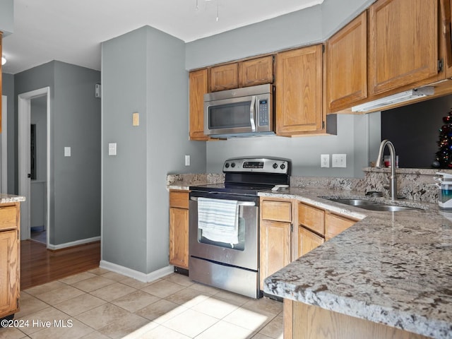 kitchen with light stone counters, light tile patterned floors, sink, and appliances with stainless steel finishes