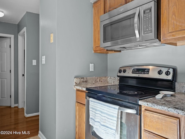 kitchen with light stone counters, dark hardwood / wood-style flooring, and stainless steel appliances