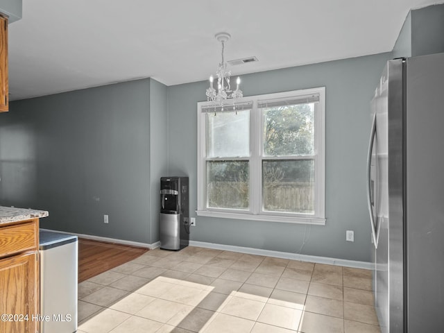 kitchen featuring stainless steel refrigerator, a chandelier, light tile patterned floors, and hanging light fixtures