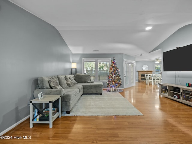 living room featuring vaulted ceiling, light hardwood / wood-style flooring, and ceiling fan