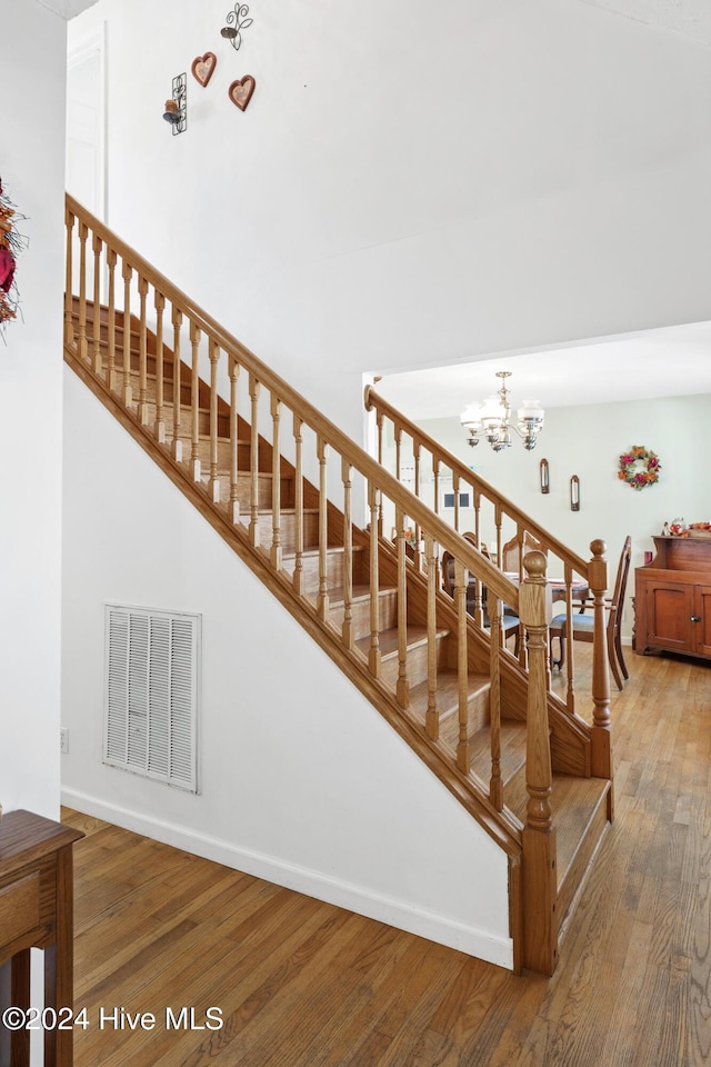 stairs featuring hardwood / wood-style floors and a chandelier