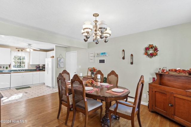 dining room with ceiling fan with notable chandelier, light wood-type flooring, and sink