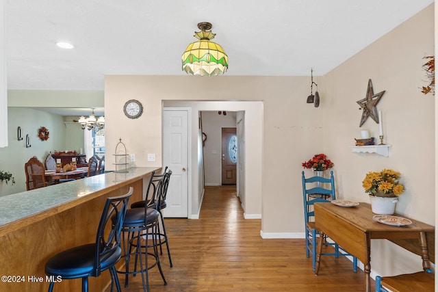 kitchen with hardwood / wood-style flooring, a notable chandelier, a kitchen bar, and hanging light fixtures