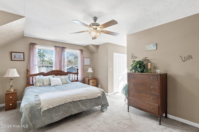 bedroom with a textured ceiling, ceiling fan, light colored carpet, and lofted ceiling