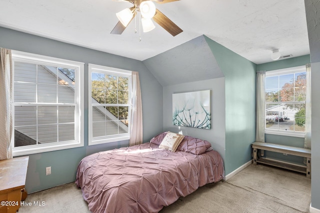 carpeted bedroom featuring multiple windows, ceiling fan, and vaulted ceiling