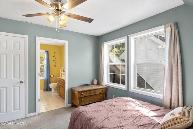 bedroom with ensuite bath, light carpet, and ceiling fan