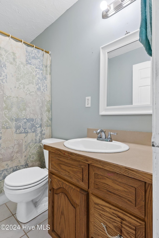 bathroom with tile patterned flooring, vanity, toilet, and a textured ceiling