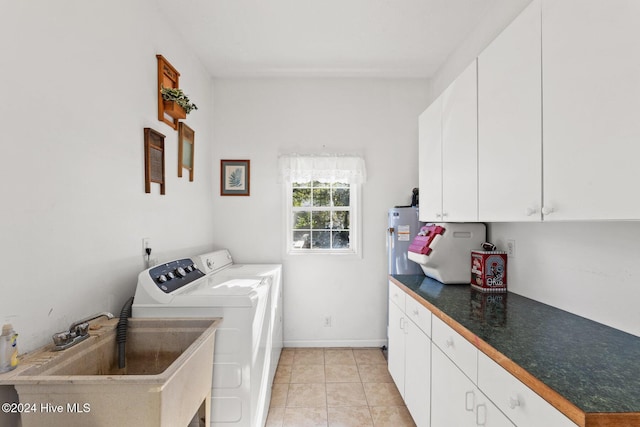 clothes washing area featuring washer and clothes dryer, light tile patterned flooring, cabinets, and sink