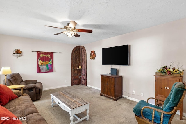 carpeted living room featuring a textured ceiling and ceiling fan