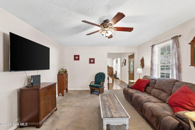 living room with a textured ceiling, light colored carpet, and ceiling fan