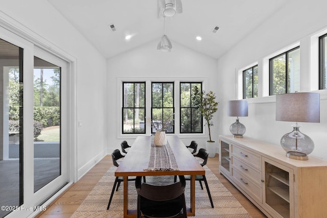 dining room with light wood-type flooring, visible vents, and lofted ceiling