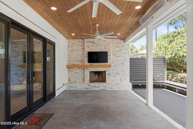 unfurnished sunroom with a ceiling fan and an outdoor brick fireplace