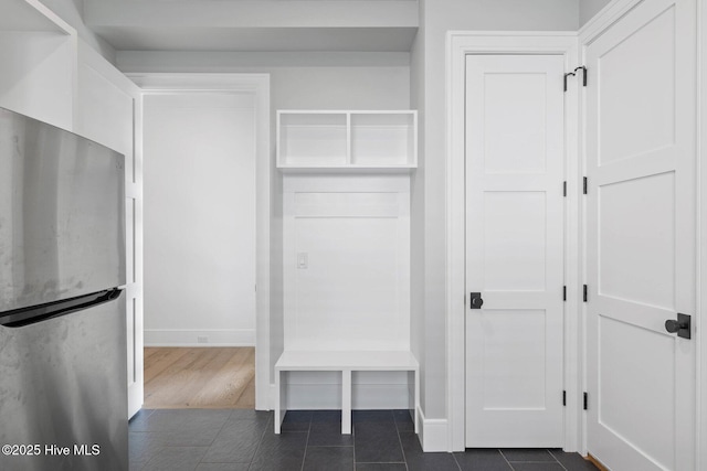 mudroom with dark tile patterned flooring and baseboards