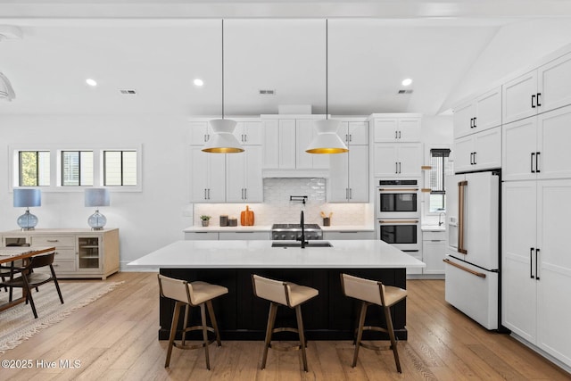 kitchen featuring high end fridge, double oven, decorative backsplash, light wood-style floors, and light countertops