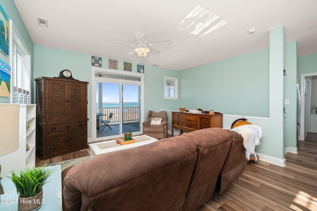 living area featuring ceiling fan, a water view, wood finished floors, visible vents, and baseboards