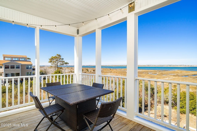 sunroom / solarium with a water view, outdoor dining area, and a beach view
