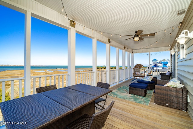 sunroom featuring ceiling fan, a beach view, a water view, and track lighting