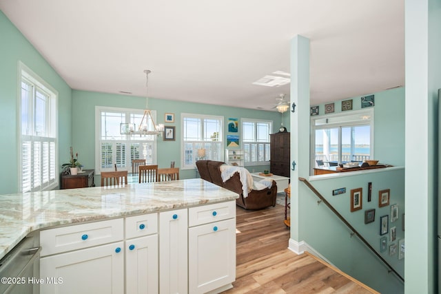 kitchen featuring pendant lighting, white cabinetry, light stone counters, open floor plan, and light wood finished floors