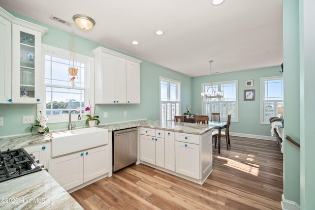 kitchen with a peninsula, white cabinetry, visible vents, stainless steel dishwasher, and a sink
