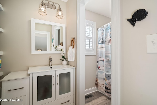 bathroom featuring baseboards, visible vents, a shower with curtain, wood finished floors, and vanity