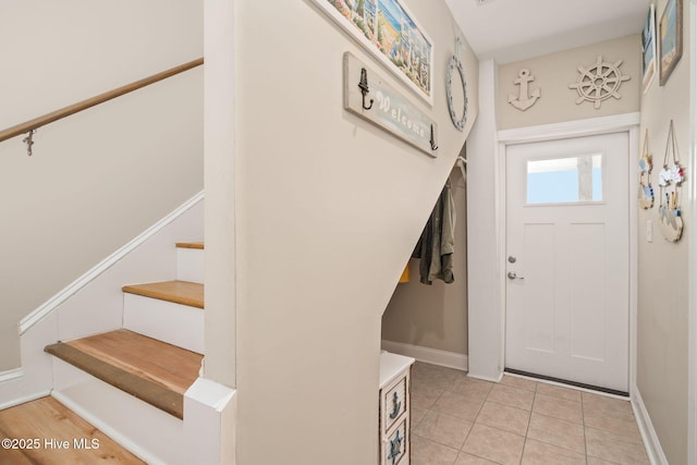 entryway with baseboards, stairway, and light tile patterned flooring