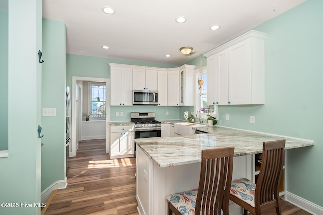 kitchen featuring a peninsula, appliances with stainless steel finishes, open shelves, and white cabinetry