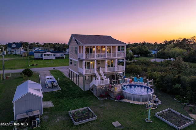 119 E Dr, Harkers Island, NC 28531 - back of house with a vegetable garden, a balcony, a shingled roof, and a yard