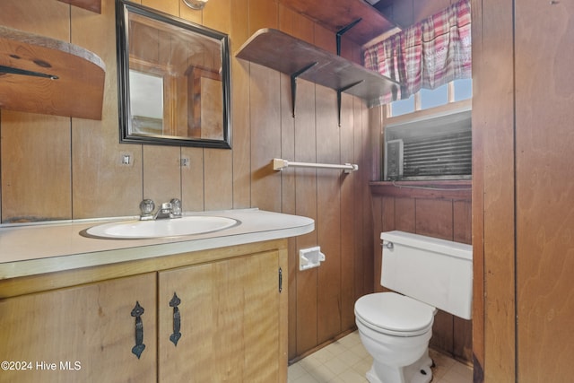 bathroom with vanity, toilet, and wooden walls